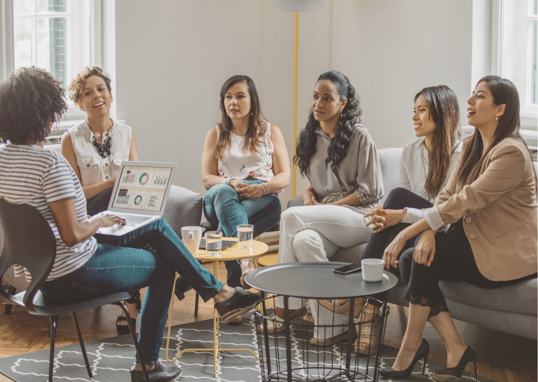 Grupo de mulheres reunidas num ambiente acolhedor, partilhando ideias numa mesa de networking